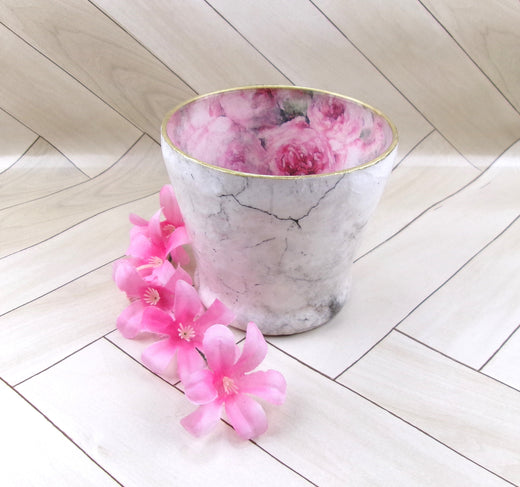 Glass vase reversed decoupaged with pink floral interior and white marble exterior with a blue and pink candle and pink and white flowers on white wood plank background from DeocupageNapkins.com