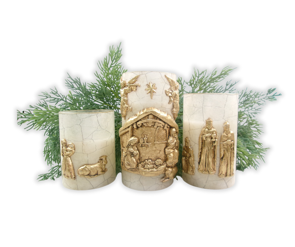 Nativity candle trio with cracked-glass rice paper and gold-gilded clay figures, styled on evergreen branches for a Christmas centerpiece.