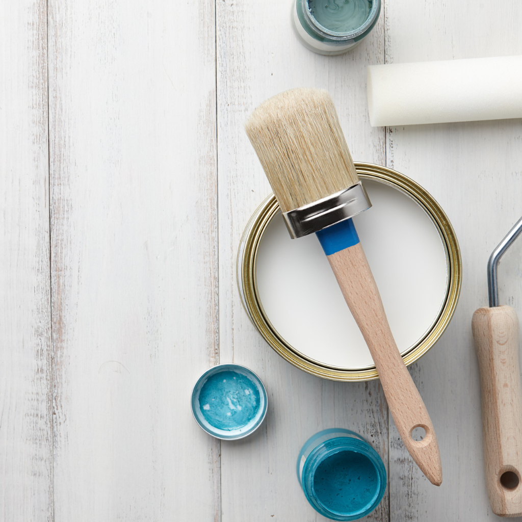 Open jars of colorful blue and green paint with paint brush.