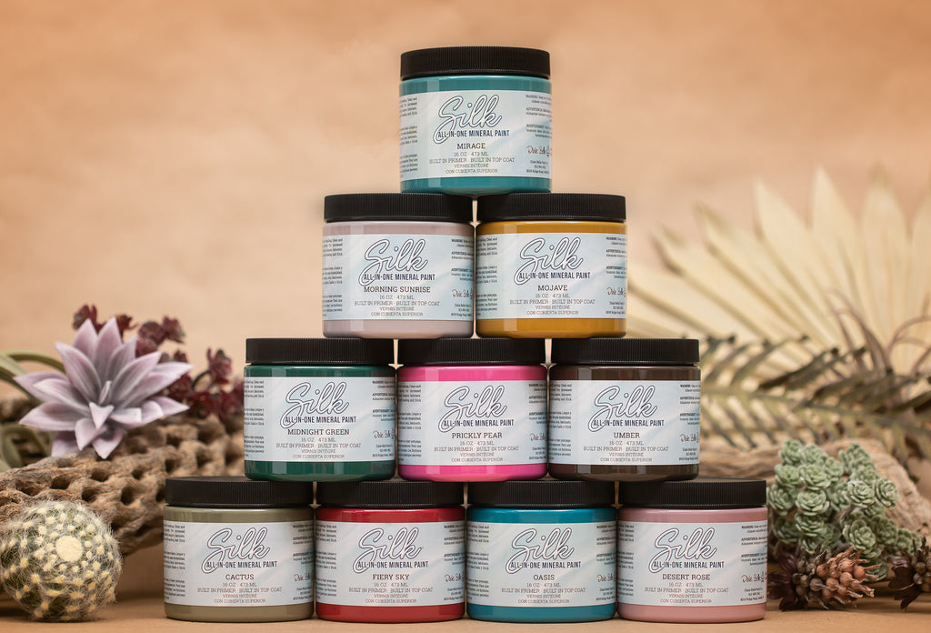 Ten stacked jars of Dixie Belle Silk All-in-one Mineral paint in a variety of colors