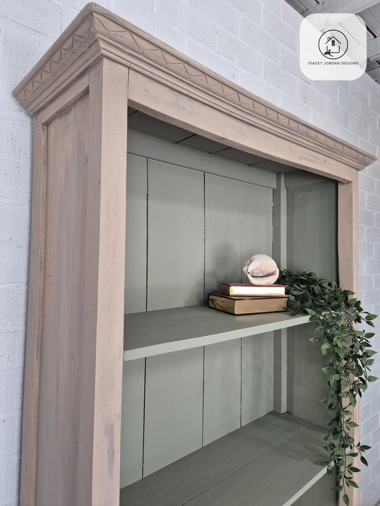 Wooden shelf with decorative items against a white brick wall