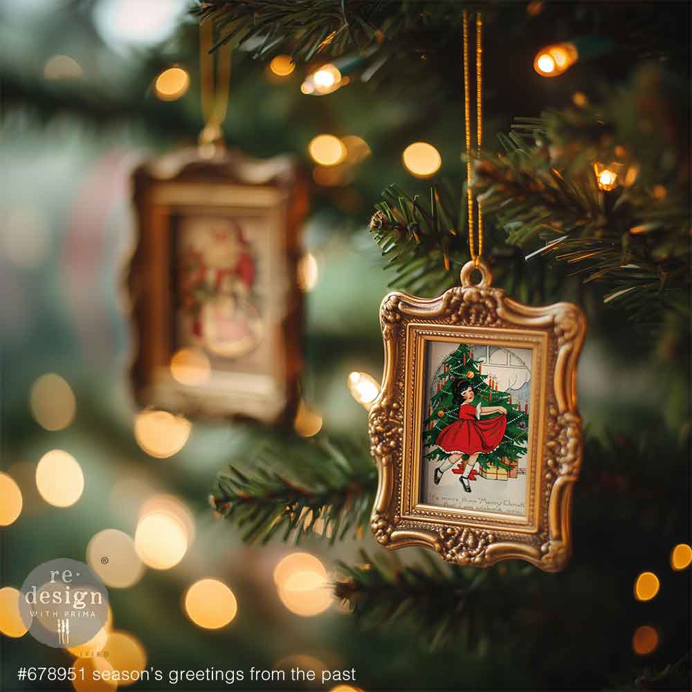Decorative Christmas ornament with a gold frame and festive design on a lit Christmas tree.