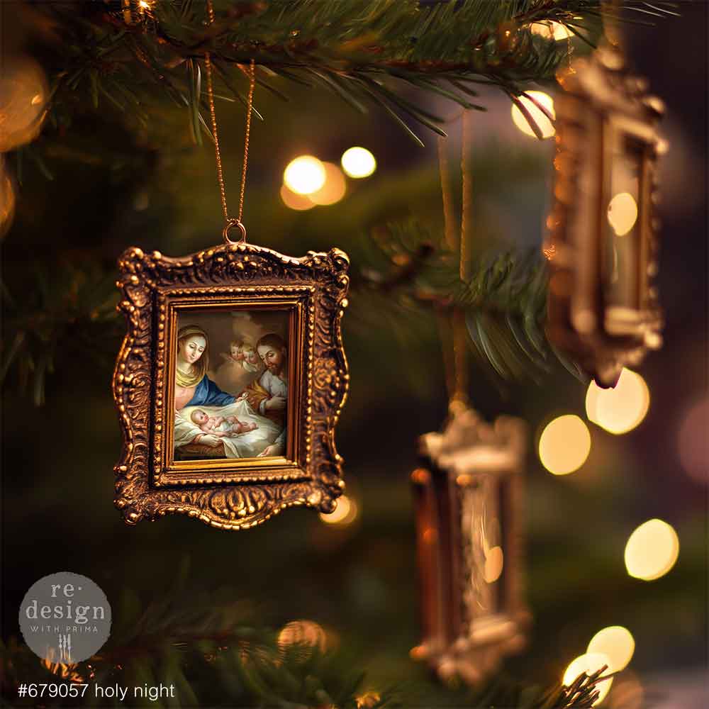 Decorative Christmas ornament of a framed nativity scene hanging on a tree.