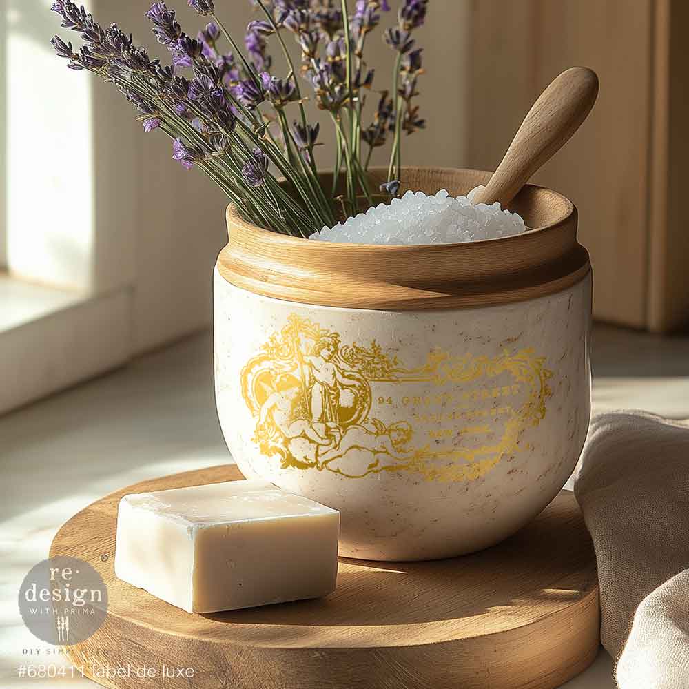 Decorative ceramic jar with gold design, wooden spoon, lavender, and soap on a wooden surface.
