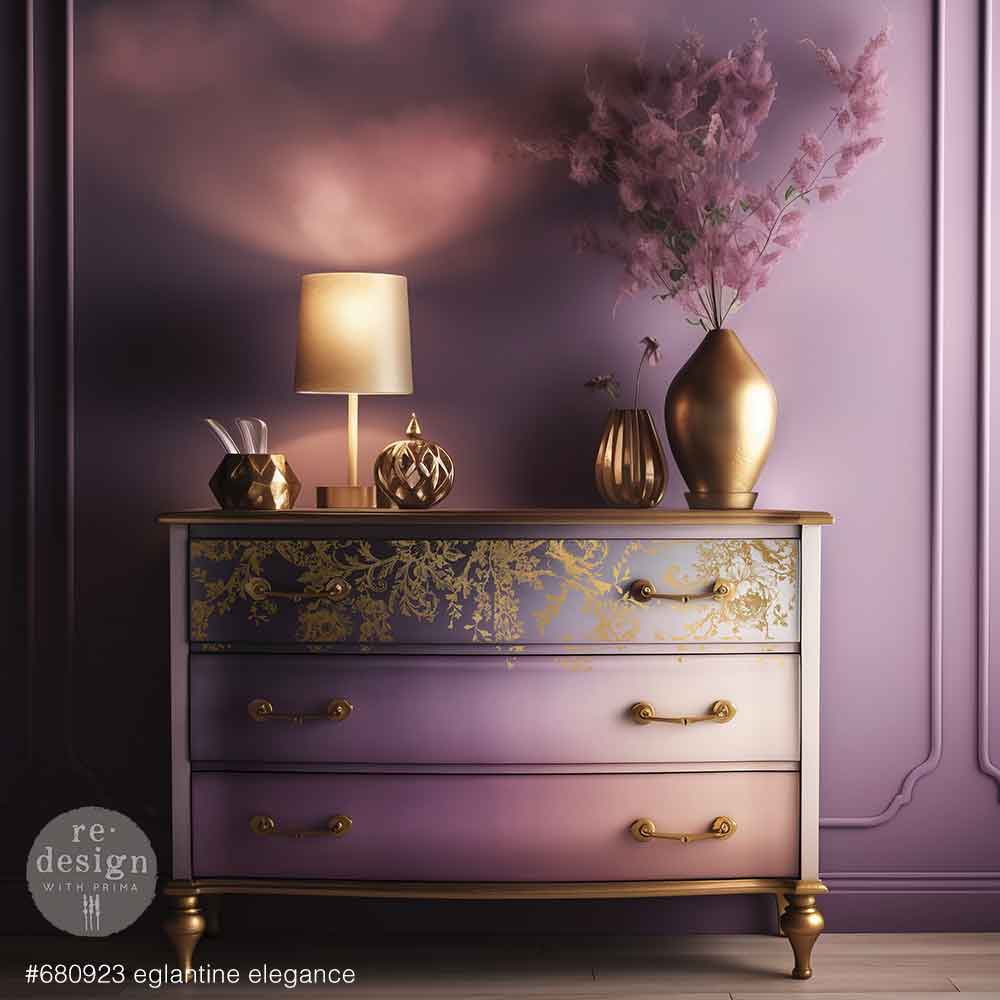 Decorative chest of drawers with gold accents and a lamp against a purple wall.
