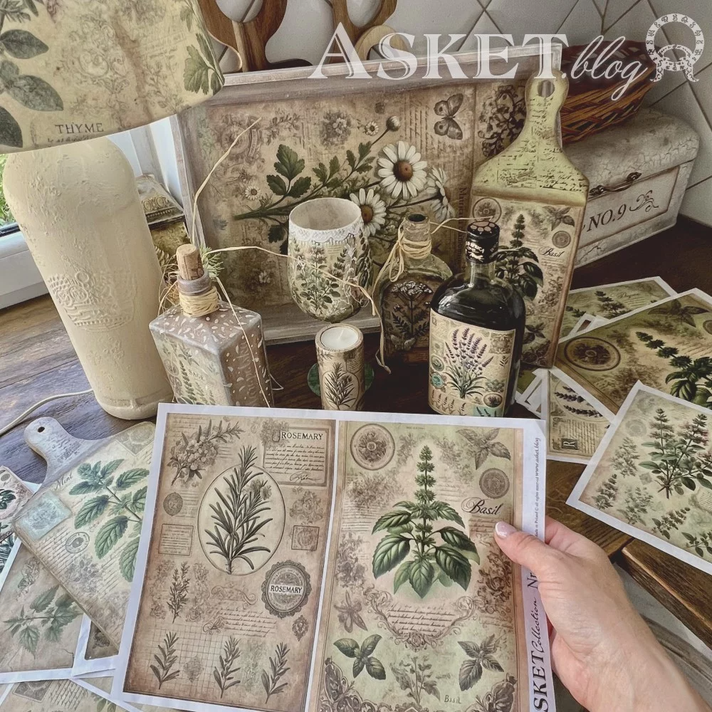 Decorative items with botanical designs on a table, including bottles, candles, and printed sheets.