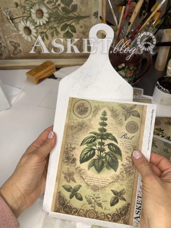 Hand holding a decorative card with botanical design on a white surface.