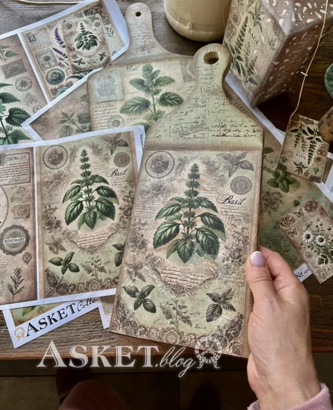 Decorative cutting board with botanical design held by a hand, surrounded by similar products on a wooden surface.