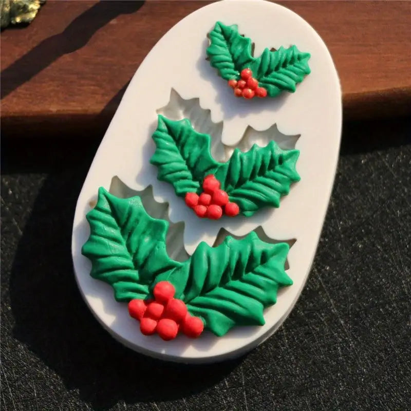Silicone mold with holly leaf and berry designs on a dark surface