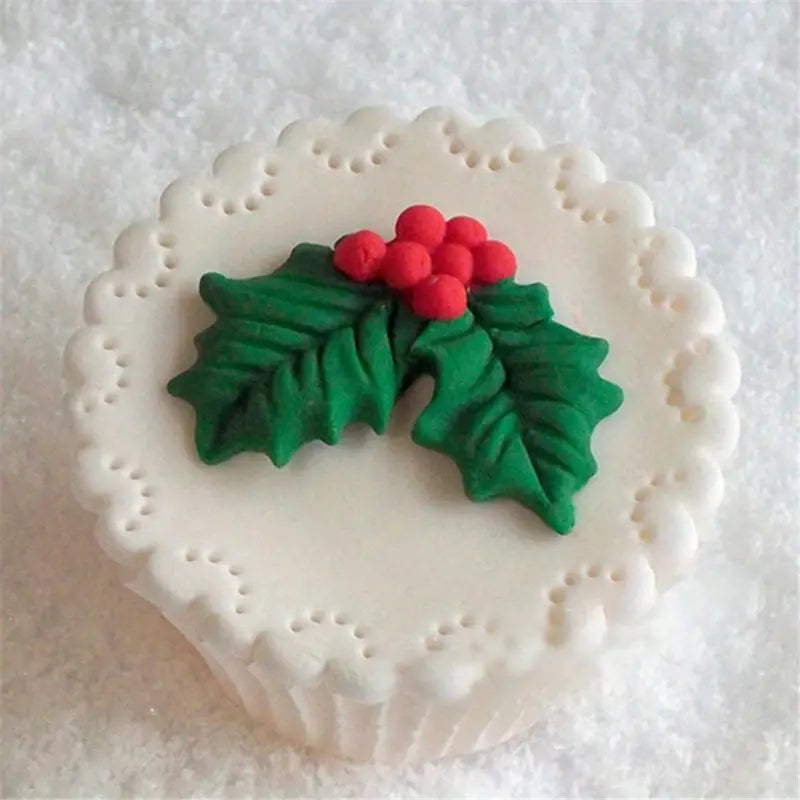 Decorative cookie with green holly leaves and red berries on a white background