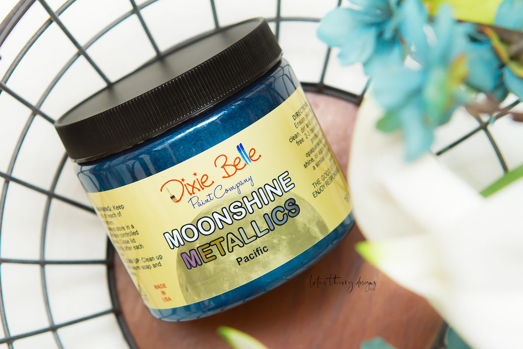 Jar of Dixie Belle Moonshine Metallics paint in the color Pacific, a bright blue shade.