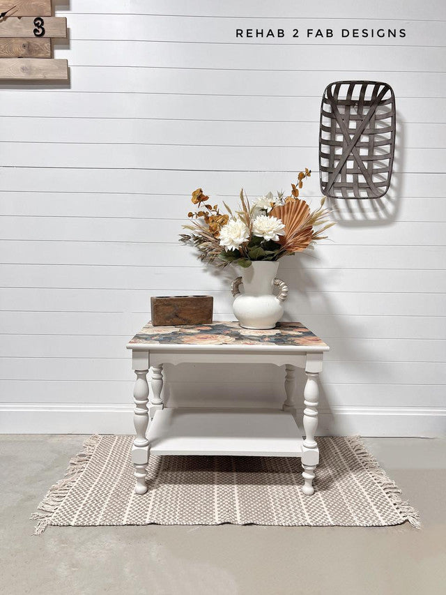 White side table with decorative items against a white wall, featuring 'Rehab 2 Fab Designs' branding.