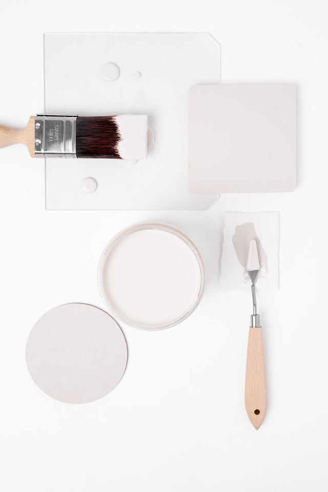 Paintbrush, paint container, and spatula on a white background