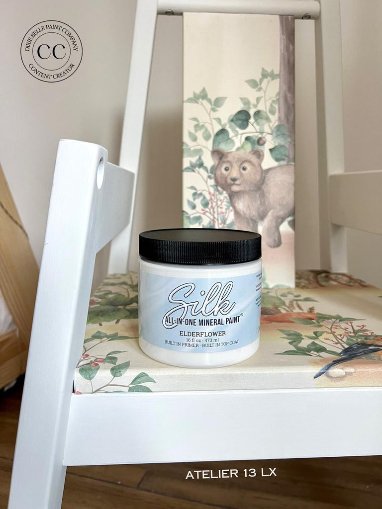 Jar of Silk all-in-one mineral paint on a decorative surface with a teddy bear illustration in the background.