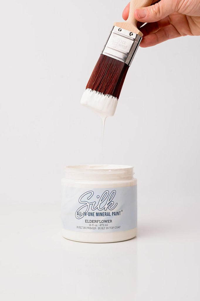 Silk All-in-One Mineral Paint jar with a brush applying paint on a white background