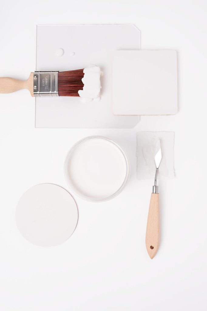 Paintbrush, paint container, and spatula on a white background