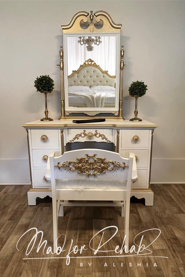 Decorative vanity with mirror, chair, and small plants on a wooden floor.