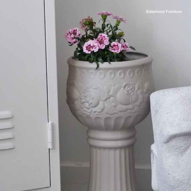 Decorative gray urn with pink flowers against a neutral background