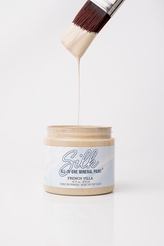 Jar of Silk all-in-one mineral paint with a brush dipping into it on a white background
