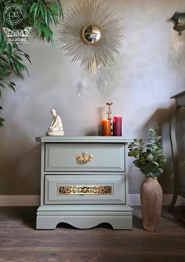 Decorative nightstand with candles, statue, and plants against a neutral wall.