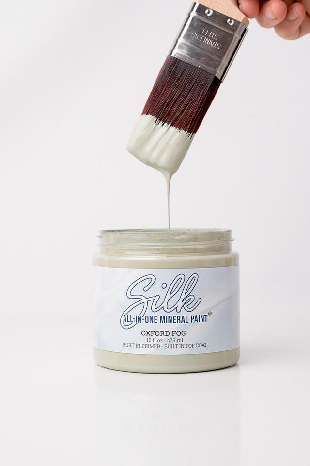 Silk all-in-one mineral paint jar with a brush dipping into it, on a white background