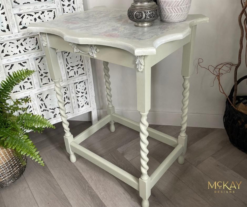 Small white table with marble top in a room setting, featuring decorative elements.
