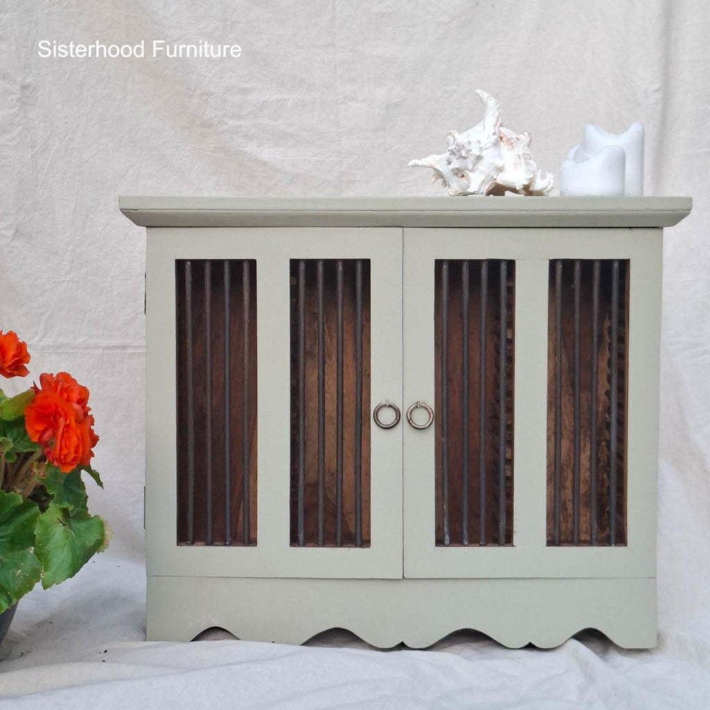 Light green cabinet with wooden panels on a white background, featuring 'Sisterhood Furniture' branding.