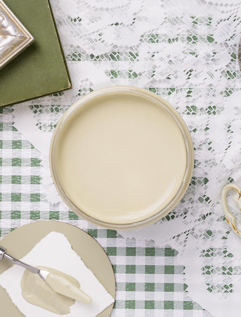 Round beige ceramic plate on a checkered tablecloth with a green box and white napkin.
