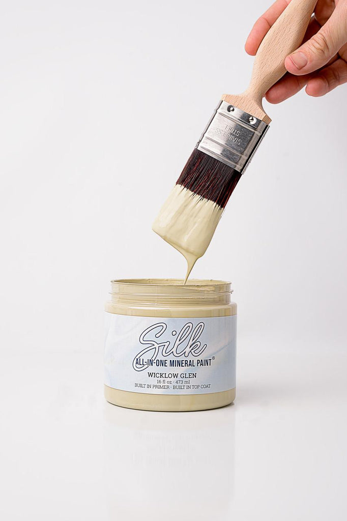 Person using a paintbrush to apply Silk All-In-One Mineral Paint from a container on a white background
